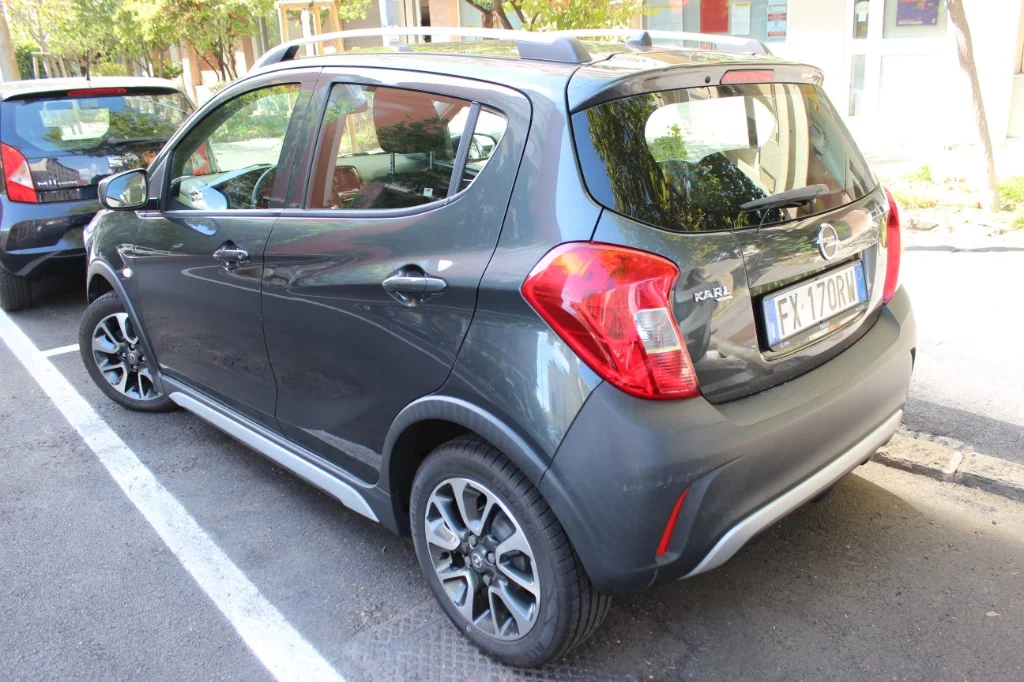 Vista posteriore Opel Karl Rocks grigio scuro con barre portatutto per noleggio auto a Trieste — LILO Autonoleggio